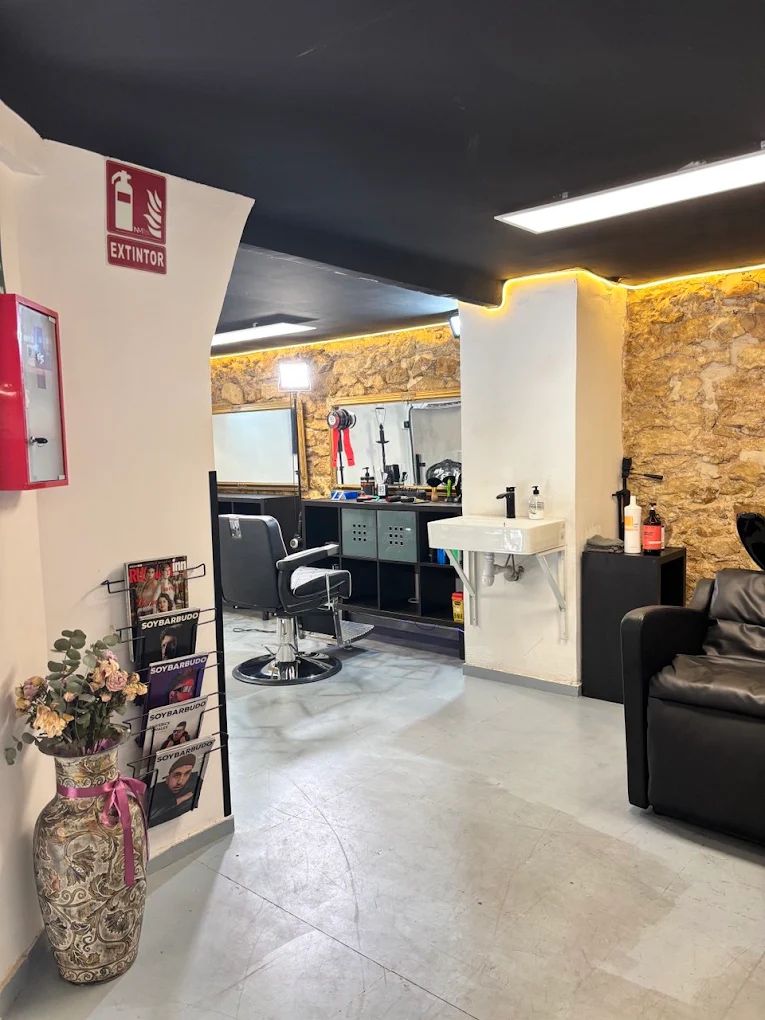 Sala de barbería con pared de piedra iluminada y sofá de cuero
